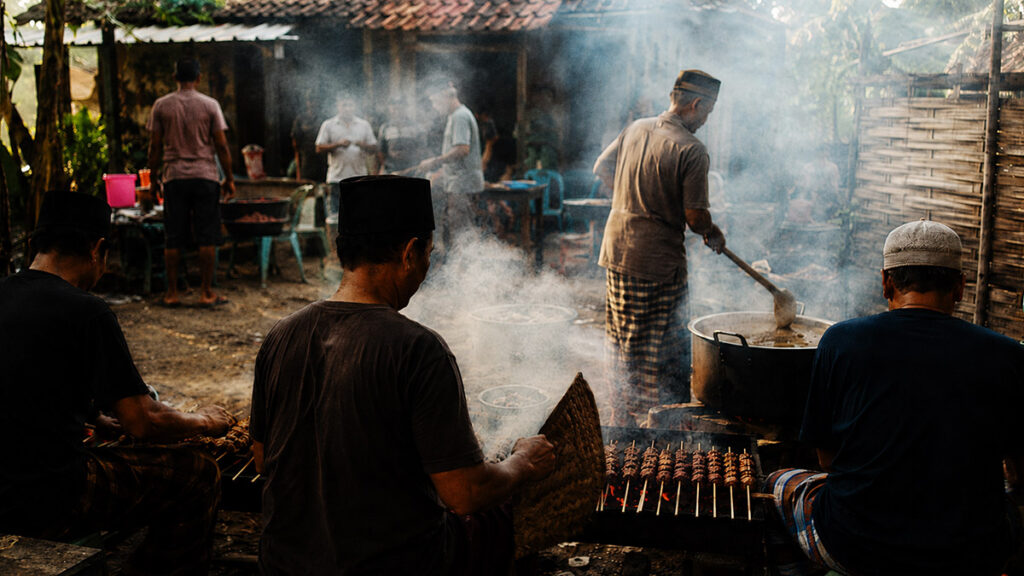 Suasana warga memasak sate daging kambing dan gulai saat Idul Adha dengan asap arang di lingkungan rumah