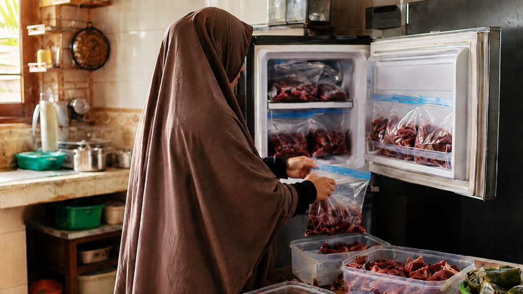 Seorang ibu menyimpan daging qurban ke freezer kulkas agar tetap segar dan awet