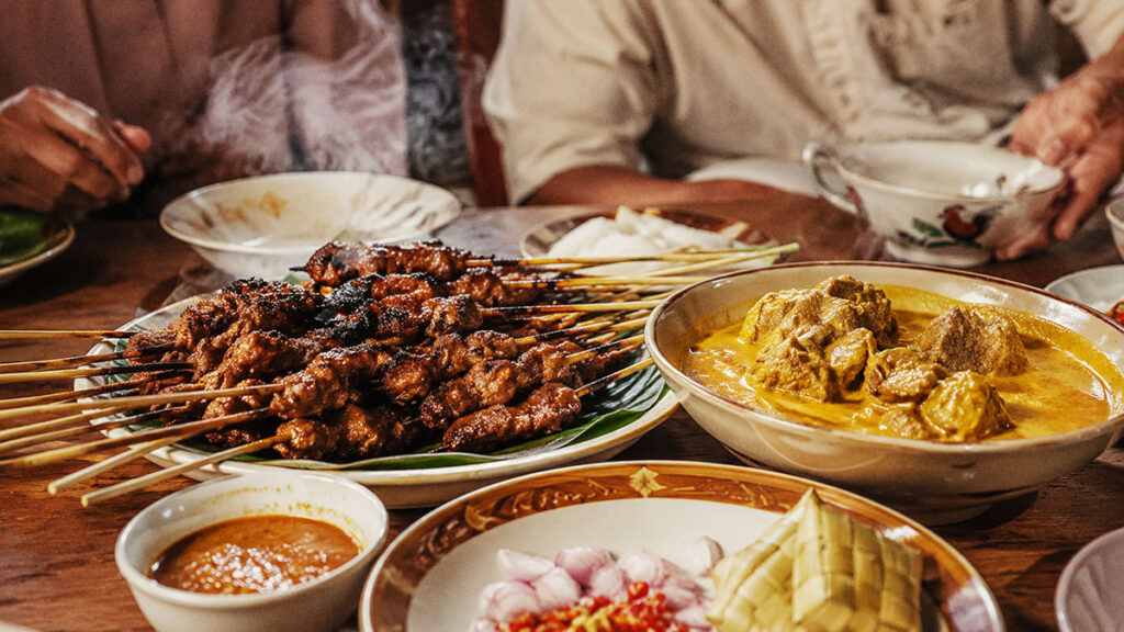 Sate dan gulai khas Indonesia disajikan hangat di meja makan keluarga saat Idul Adha