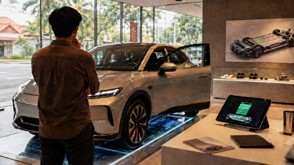 Calon pembeli melihat mobil listrik di showroom sambil mempertimbangkan umur baterai dan biaya penggantiannya.